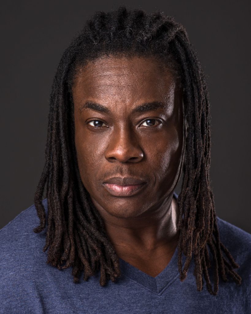 Skyler Cooper, close portrait, serious expression, wearing a blue collarless shirt.